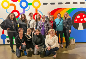 Group picture of Bridge Meadows staff team in front of a rainbow-colored mural